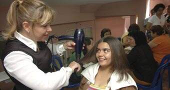 Silvana Garcia de Freitas corta cabelo da dona de casa Adriana da Silva, 23, ontem, durante o Dia da Mulher em iniciativa da DDM de Franca: valorização da auto-estima