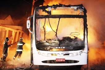 Bombeiro trabalha no que sobrou de ônibus incendiado no Jardim São Luiz: as chamas destruíram o veículo em poucos minutos