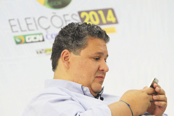 O candidato a deputado federal Corrêa Neves Jr. (PV) usa o celular, antes de sabatina, para conversar com eleitores
