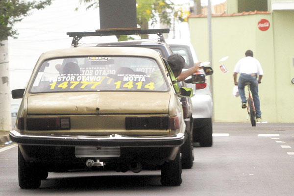Membro da equipe de campanha do Pastor Otávio Pinheiro (PTB) atira santinhos na rua, durante carreata na manhã de sábado