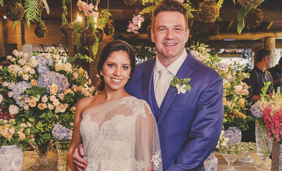 Os noivos, Valdes Jr. e Caroline recepcionando os convidados no Espaço Madeira, entre muitas flores na decoração.