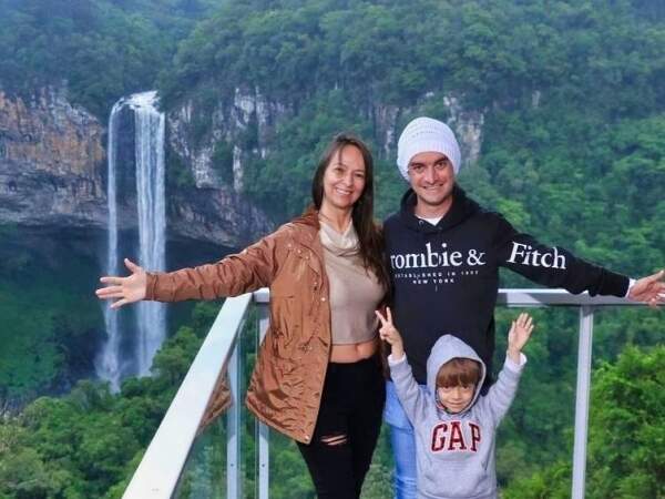 Família feliz: Tiago Crialezi, Milena Costa Crialezi e o pequeno Enzo em momento de diversão com a famosa Cachoeira do Caracol, em Gramado, ao fundo