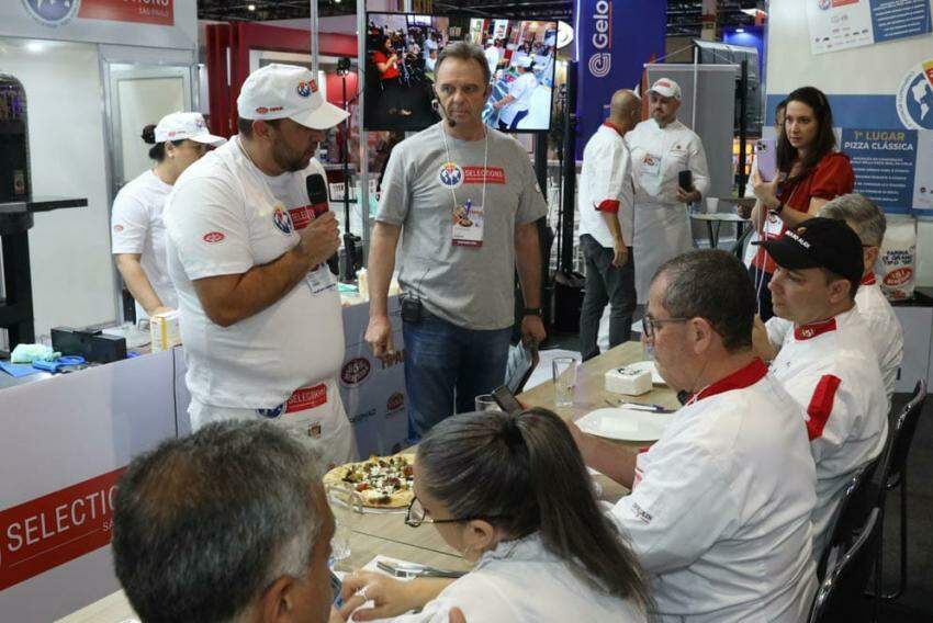Pizzaiolo Maurício Dias com microfone apresentando pizza para júri