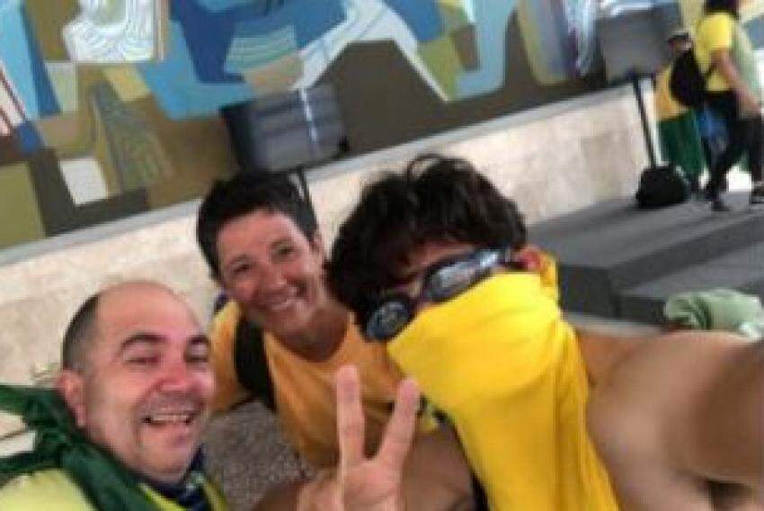 Fabrício de Moura Gomes, com um pano amarelo no rosto, junto de dois amigos no interior do Palácio do Planalto