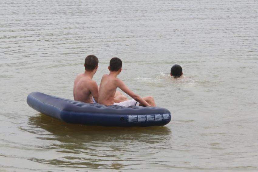 Amigos utilizando colchão inflável para se divertir na margem da lagoa