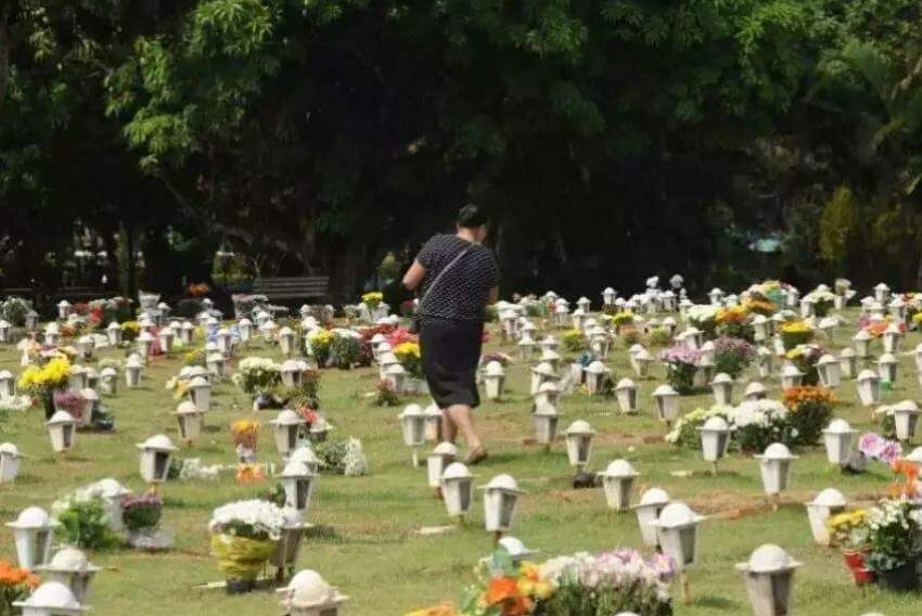 Mulher passa entre túmulos em cemitério