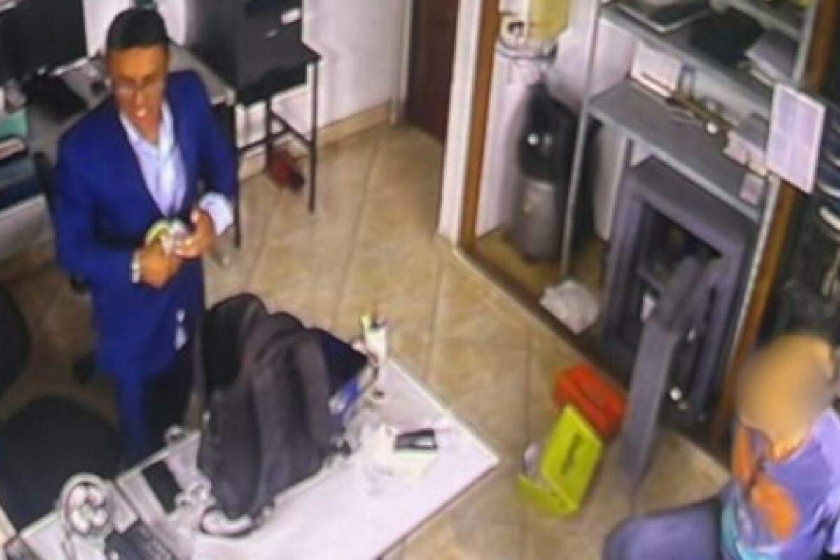 No vídeo, um dos ladrões rouba o cofre, enquanto o empresário observa a ação amarrado em uma cadeira. 
