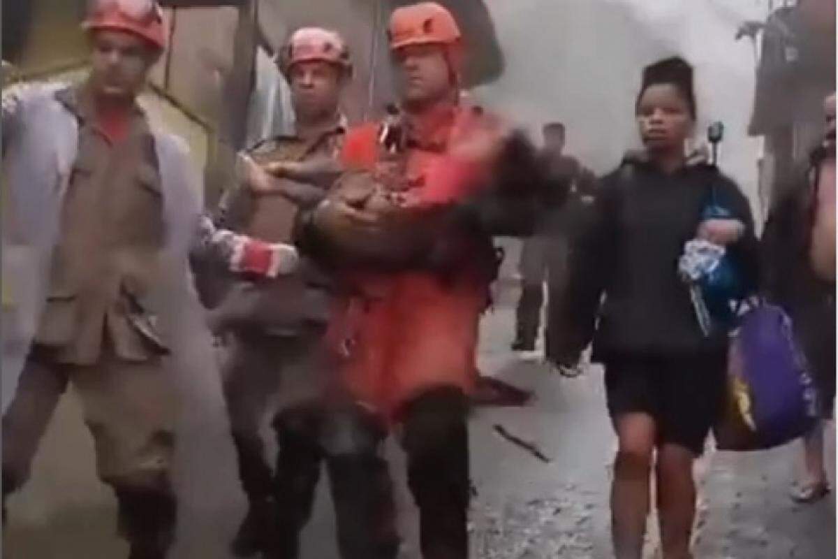 Bombeiros carregam a menina resgatada