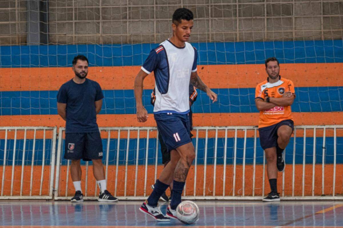 Elton Carvalho, de laranja, observa jogador durante treino do Futsal Bauru