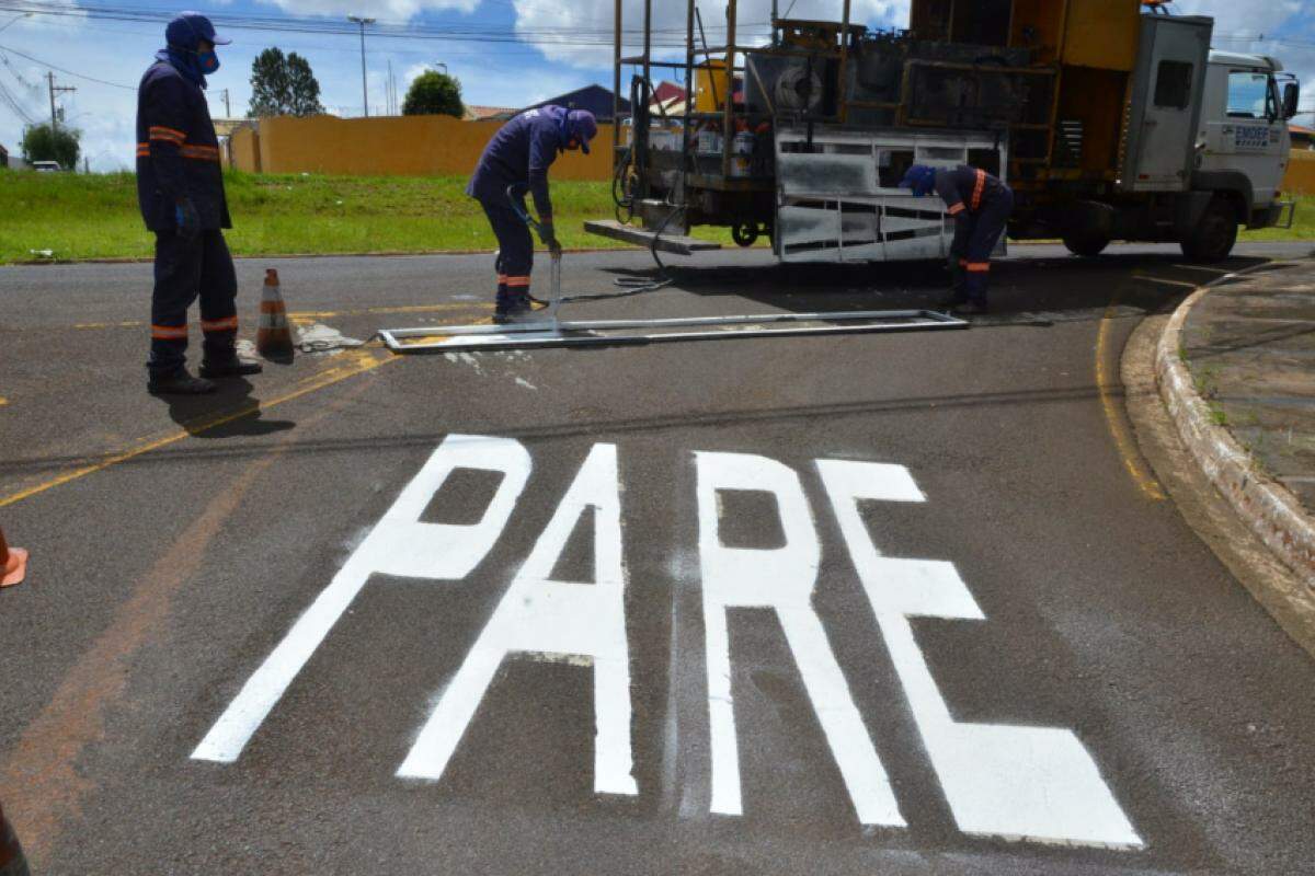 Equipe da Emdef fazendo pintura de 'Pare' em cruzamento 