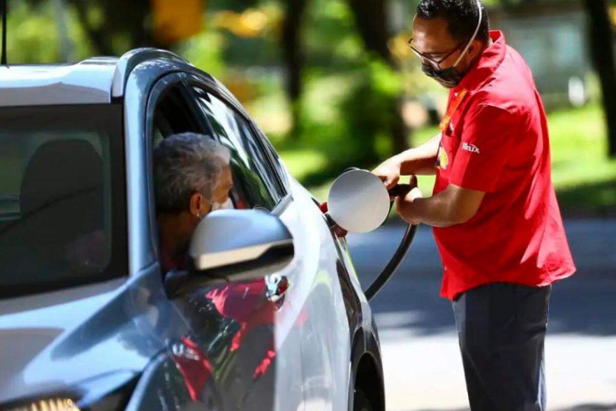 Frentista abastecendo veículo de motorista com gasolina 