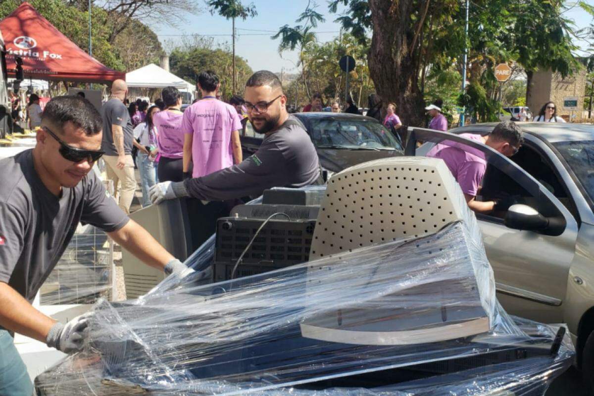 Voluntários ajudam a retirar as doações dos veículos.