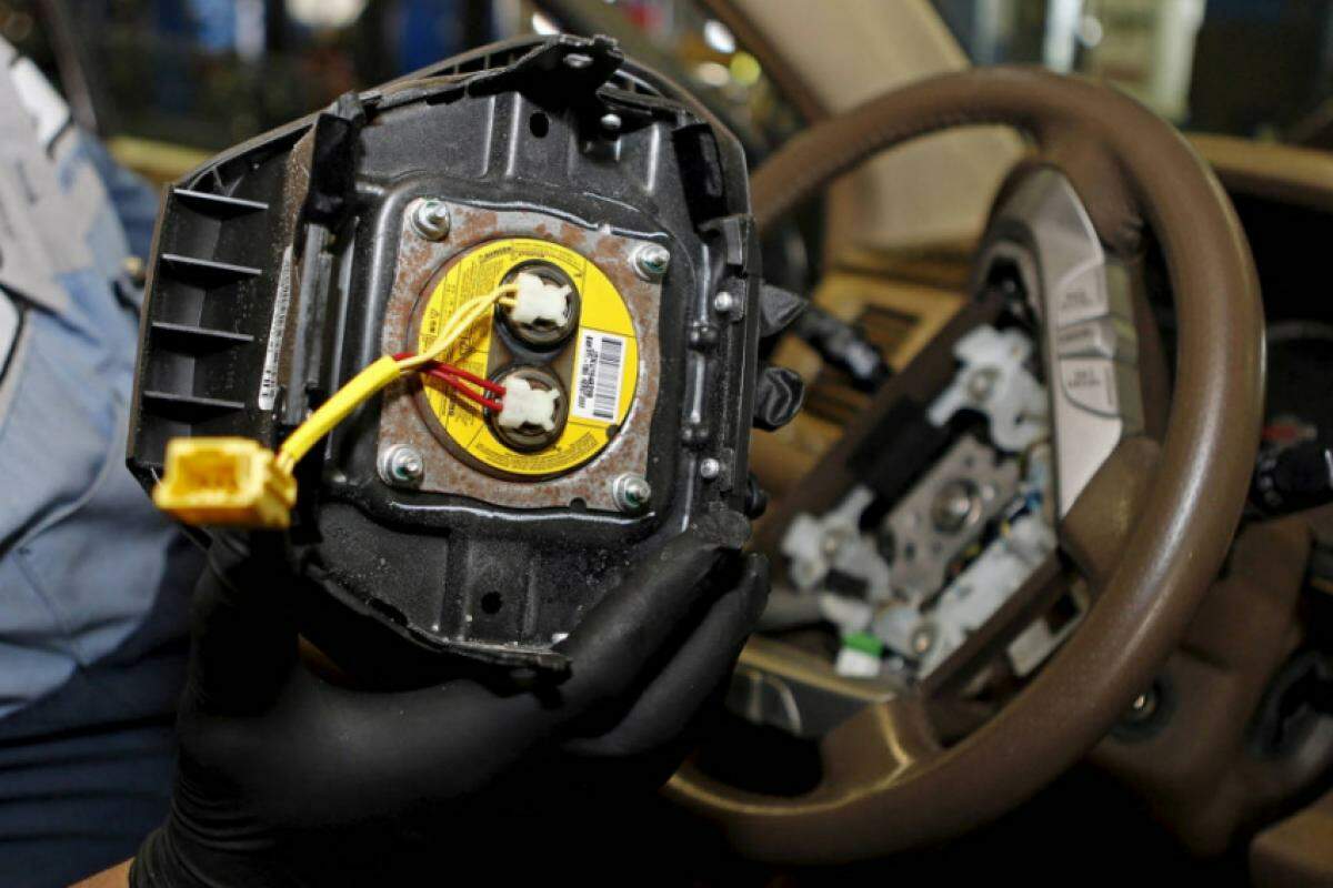 Mecânico segura um airbag Takata recolhido após recall, em Miami