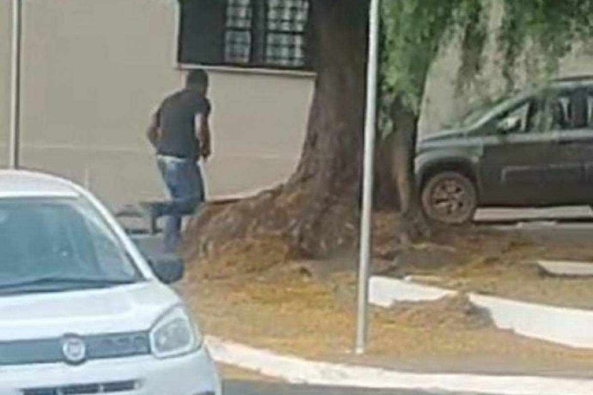 Atirador corre com a arma na mão pela avenida Major Nicácio em direção a um carro estacionado em uma praça perto da Escola Pestalozzi