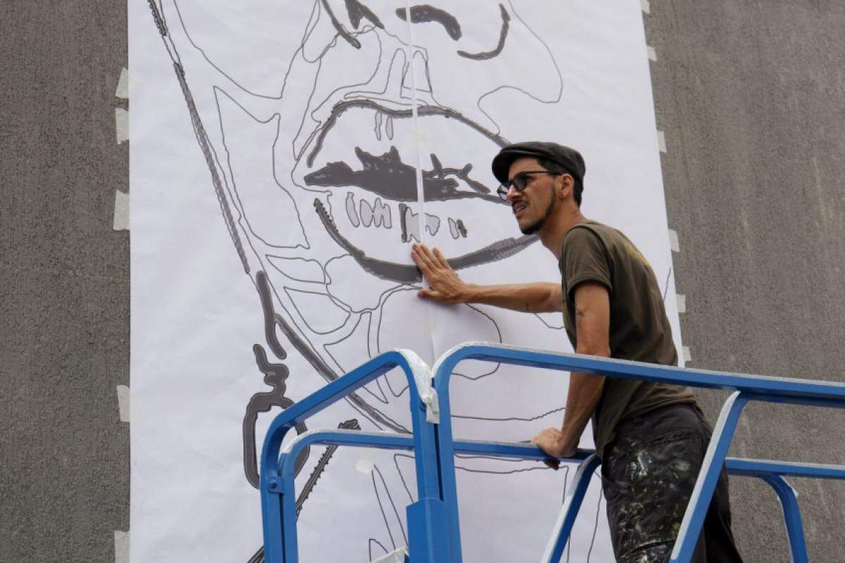 O artista Felipe Rezende, de Taubaté, criando a pintura no muro