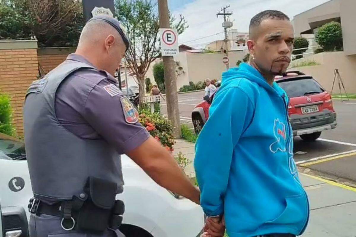 Policial militar conduz o suspeito em frente à DDM (Delegacia de Defesa da Mulher)