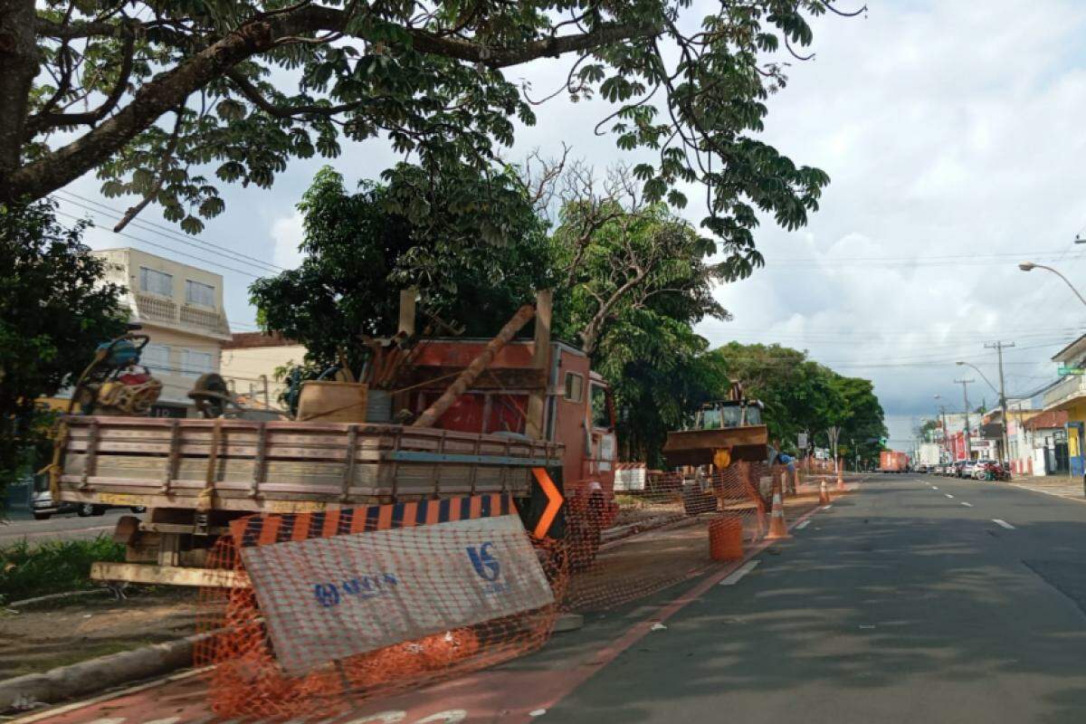 Máquinas de grande porte ocupam o canteiro central da avenida durante manutenção; trânsito é parcialmente bloqueado para segurança