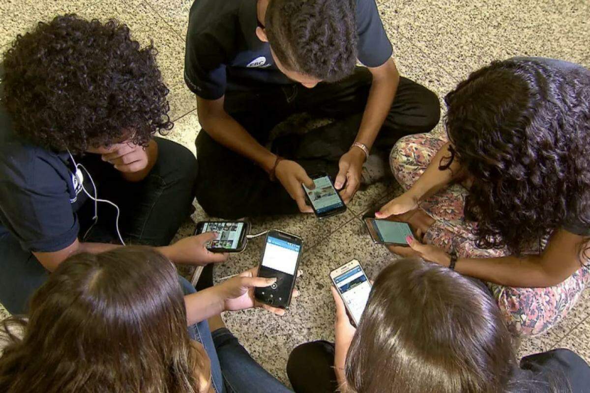 Jovens usando celulares em escola