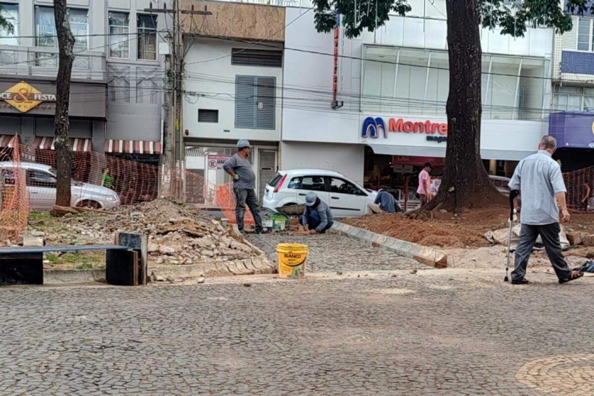 Trabalhadores realizam reparos na calçada da praça