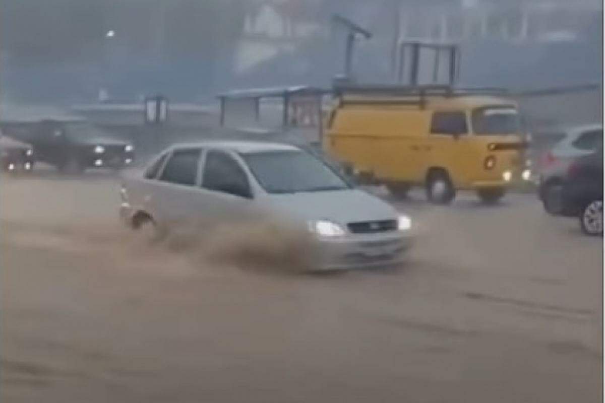 Carros passando em via alagada de São José dos Campos