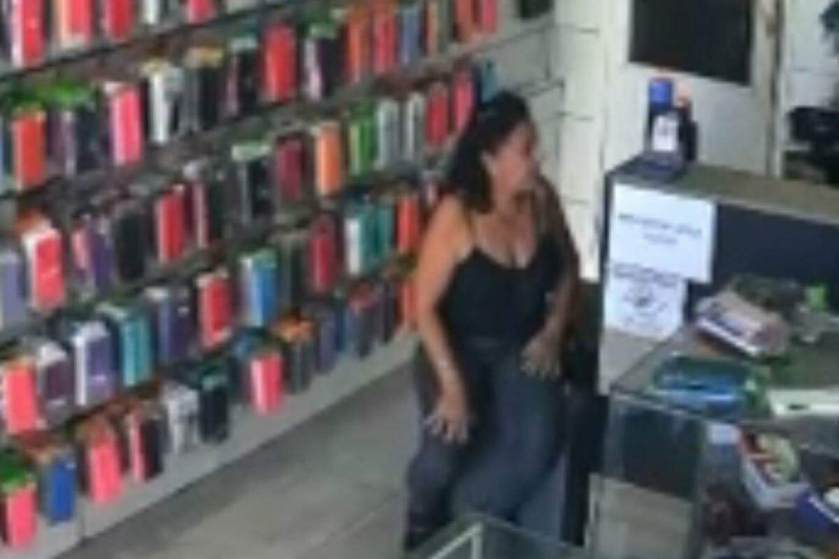 Momento em que mulher senta no banquinho e põe o pé sobre o dinheiro