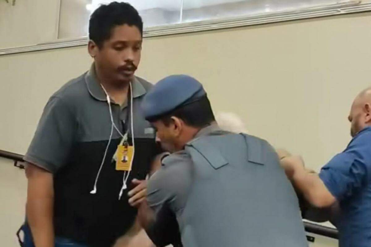 Ex vereador sendo retirado pelo policial após ordem do presidente da Câmara