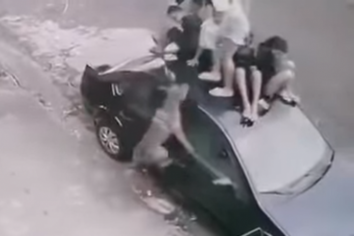 Imagens de câmra de segurança mostram as crianças desesperadas e amontoadas sobre o carro, enquanto o animal salta incansavelmente na direção delas. 
