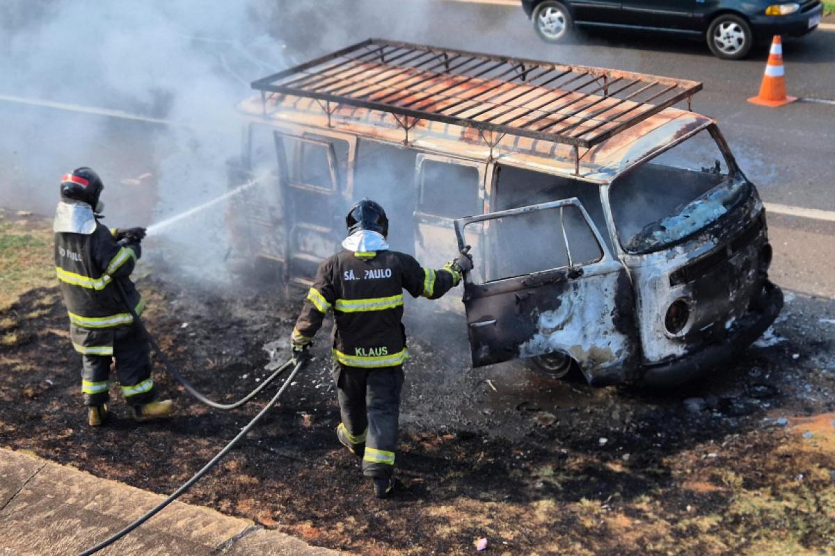 Bombeiros apagando incêndio; a Kombi ficou completamente destruída