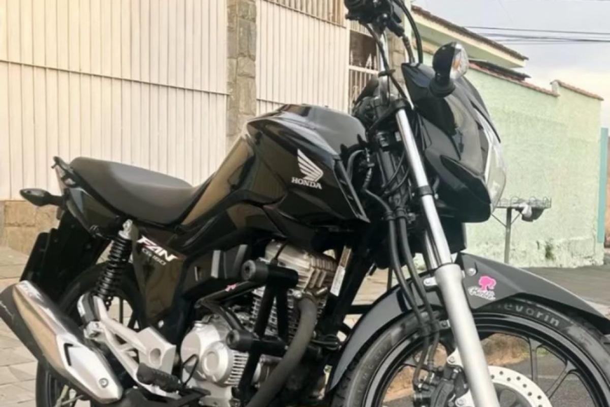 A motocicleta é uma Honda CG 150 Fan, de cor preta, utilizada diariamente pela jovem furtada no bairro São Joaquim 