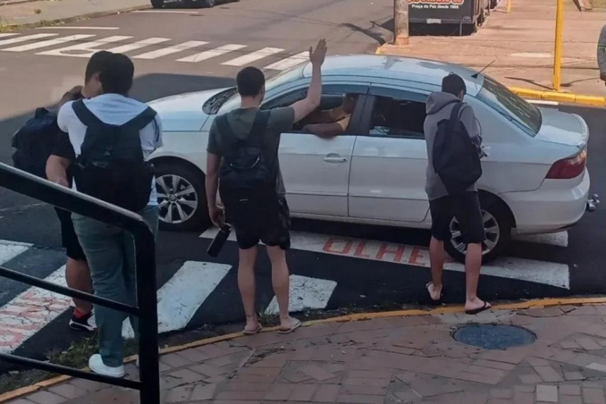 Estudantes perto do carro do motorista de aplicativo, já com o idoso dentro