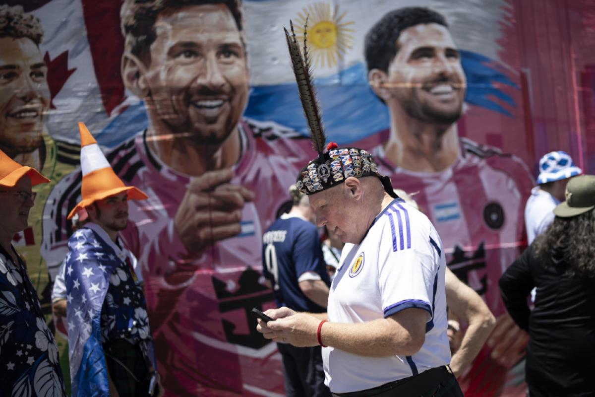 Torcedores escoceses fazem festa nas ruas de Little Havana em Miami (EUA), com imagem de Messi ao fundo