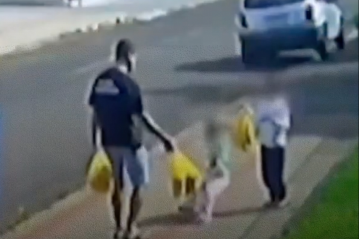 No vídeo, o pai caminha com a menina e outro filho, de cinco anos. 