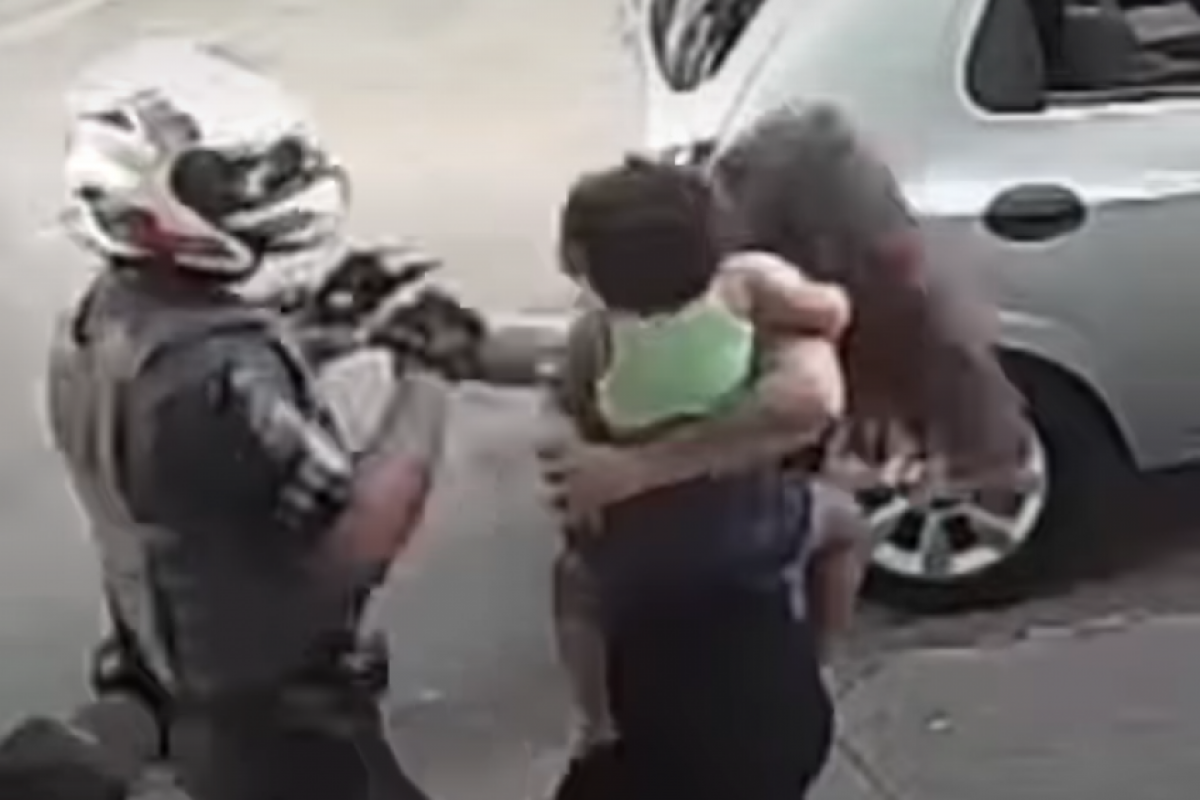 Uma mulher com bebê no colo deu tapa num policial, que revidou com um soco no rosto e a derrubou ao chão.